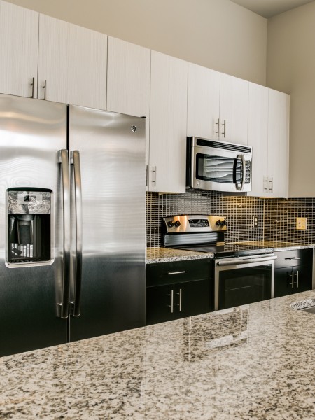 View of the Kitchen at Routh Street Flats Apartments, Showing Granite Countertop and Stainless Steel Appliances