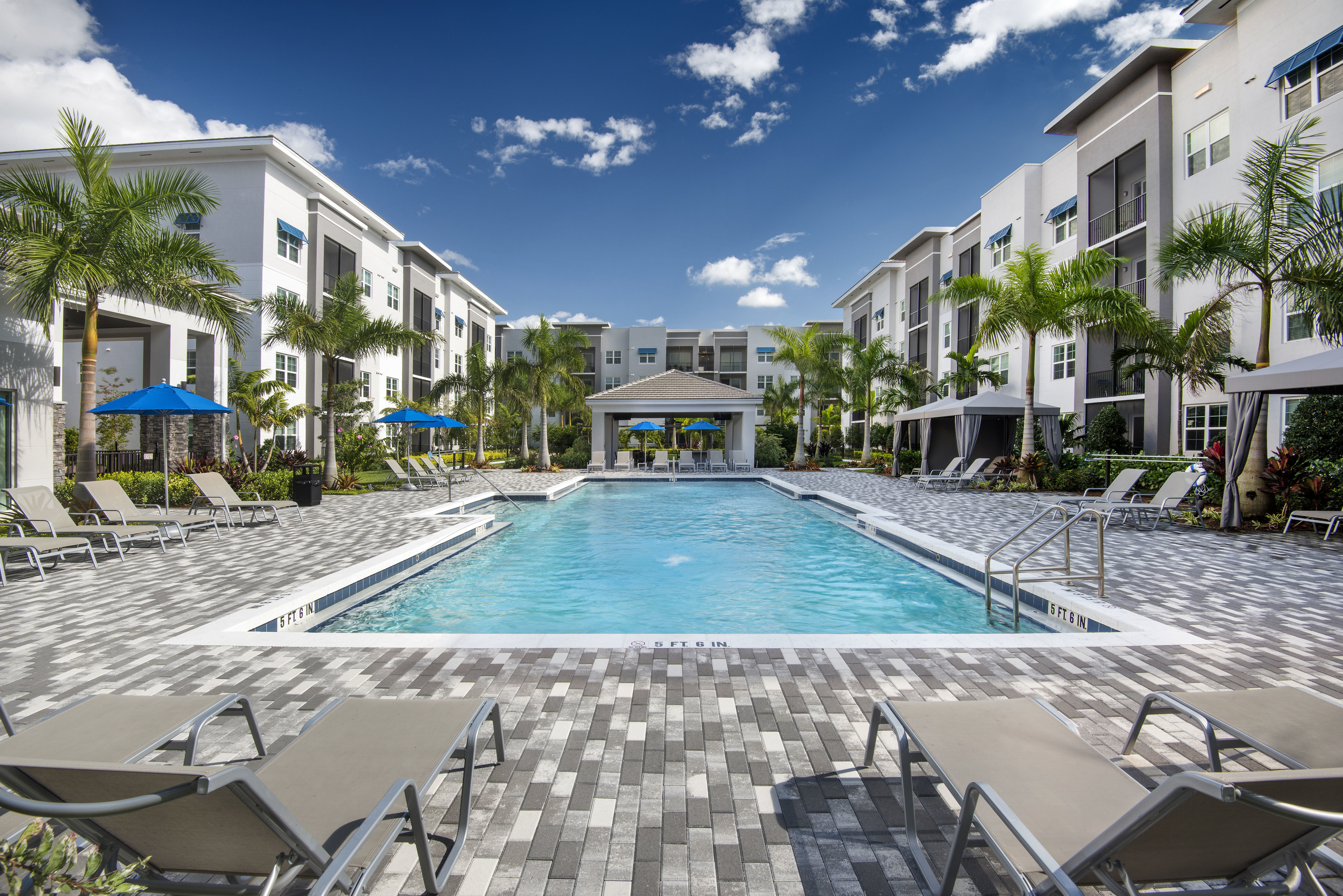 Featured Amenity  | Heated Resort Inspired Pool | Sundeck, Loungers, Cabanas, Building Exterior | Cottonwood West Palm Apartments