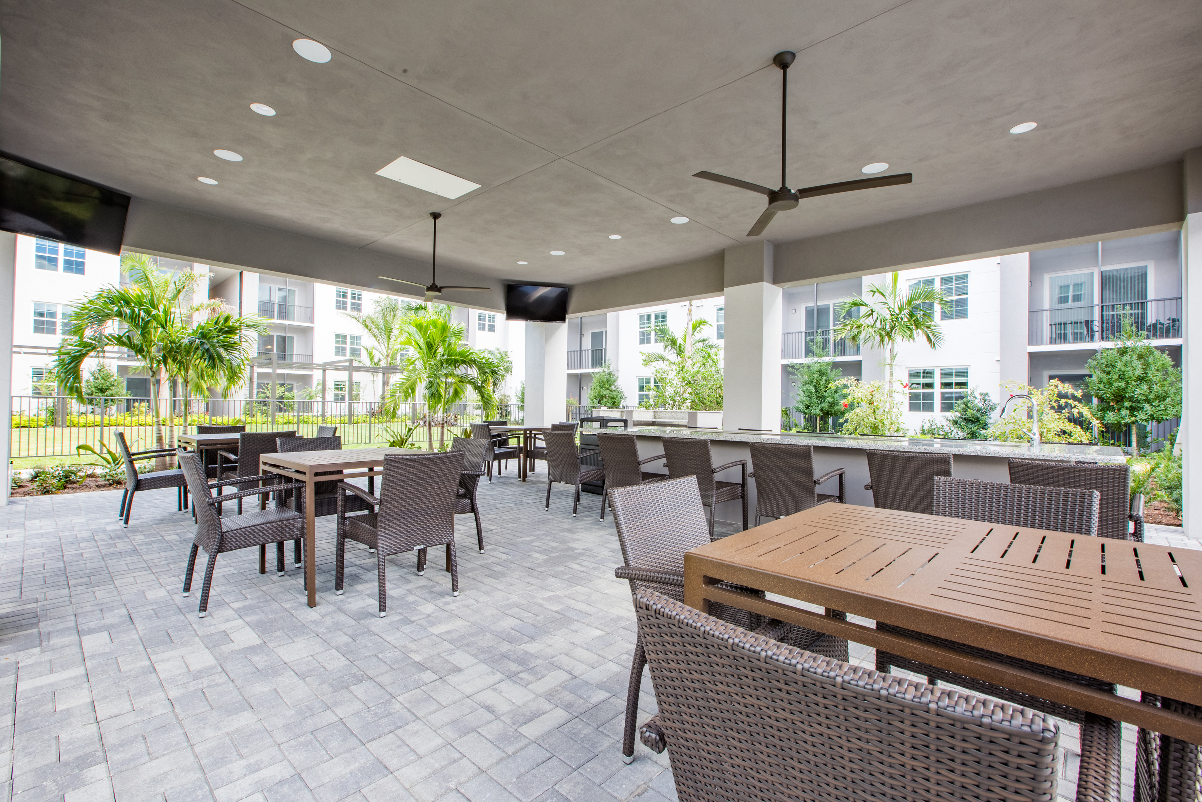 Enjoy Our Outdoor Grilling Lounge, With View of Pavilion Area, Long Granite Counter Table, and Grill at Cottonwood West Palm Apartments