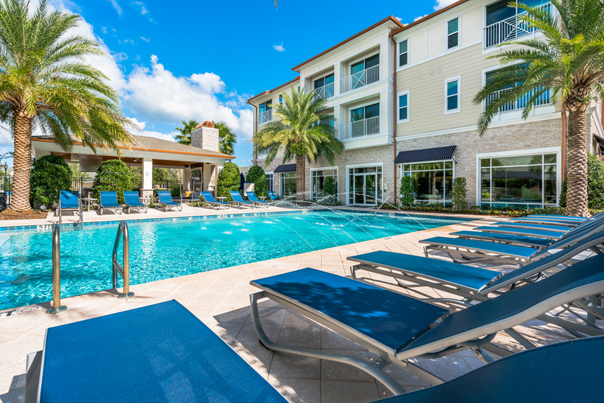 View of Pool Area, Showing Loungers, Palm Trees, Grilling Lounge, and Building at The Marq Highland Park Apartments