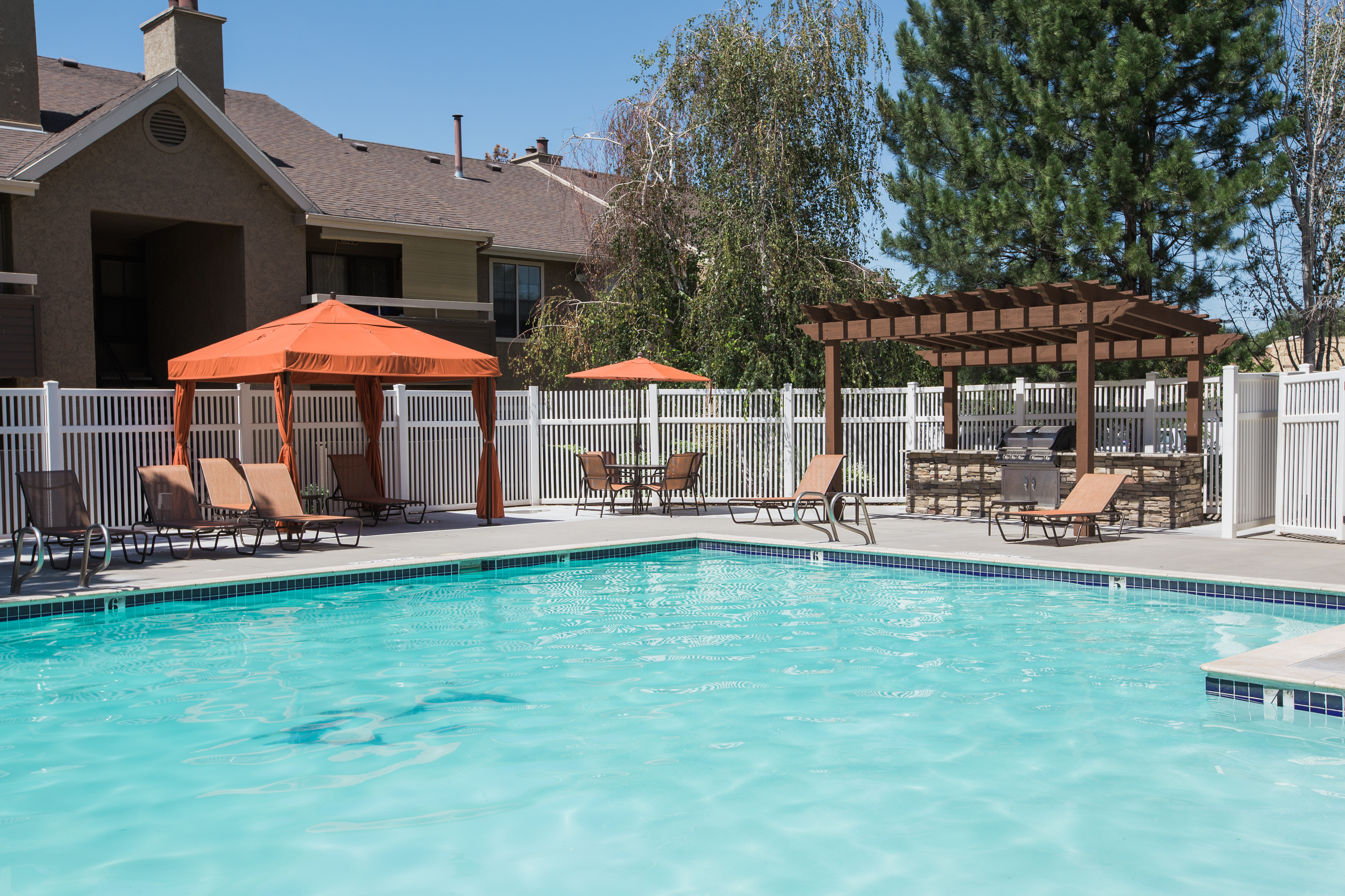 View of Pool, Showing Loungers, Cabanas, and Grilling Area with Pergola at Cottonwood Apartments