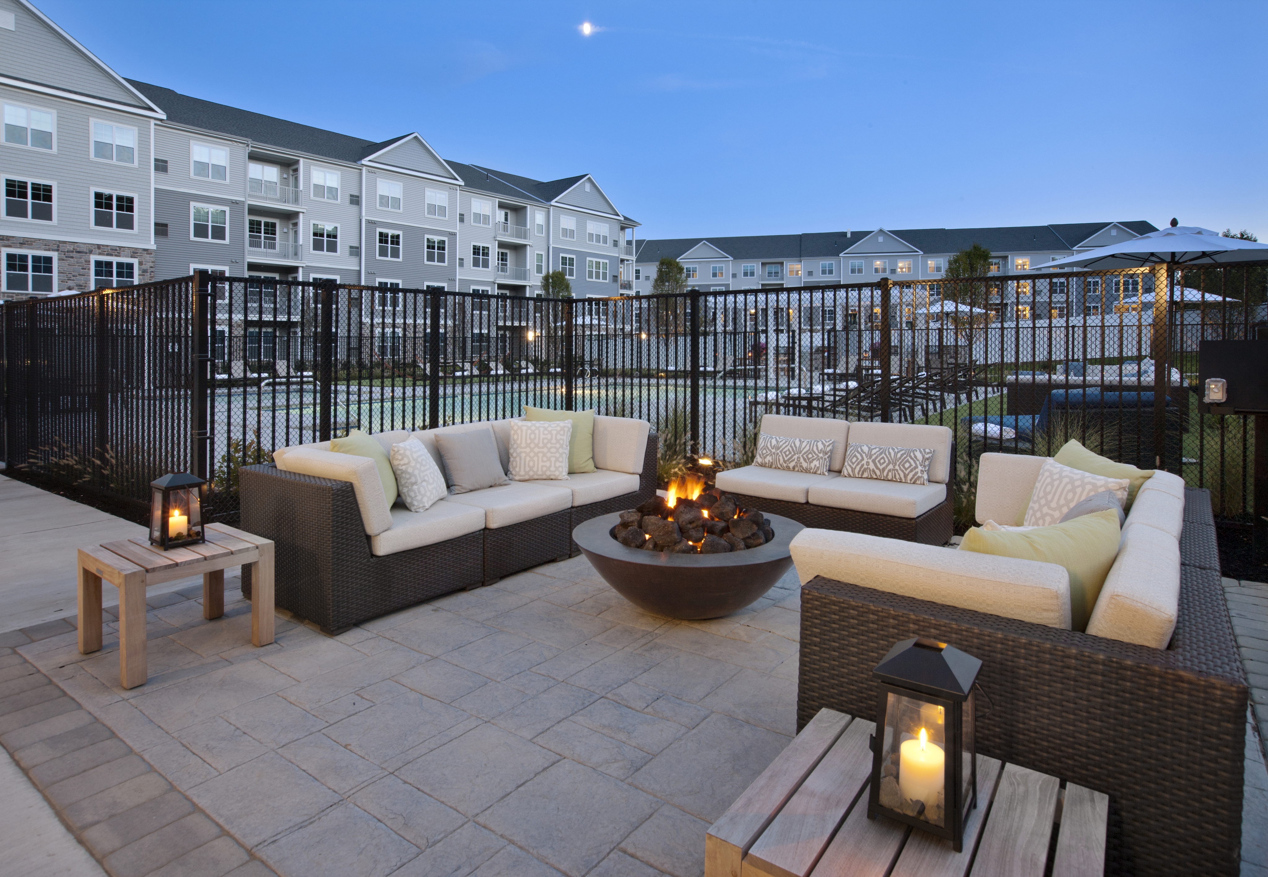 View of Pool Area, Showing Outdoor Couches, Firepit, Fenced-In Pool, and Apartment Buildings in Background at Parc Westborough Apartments