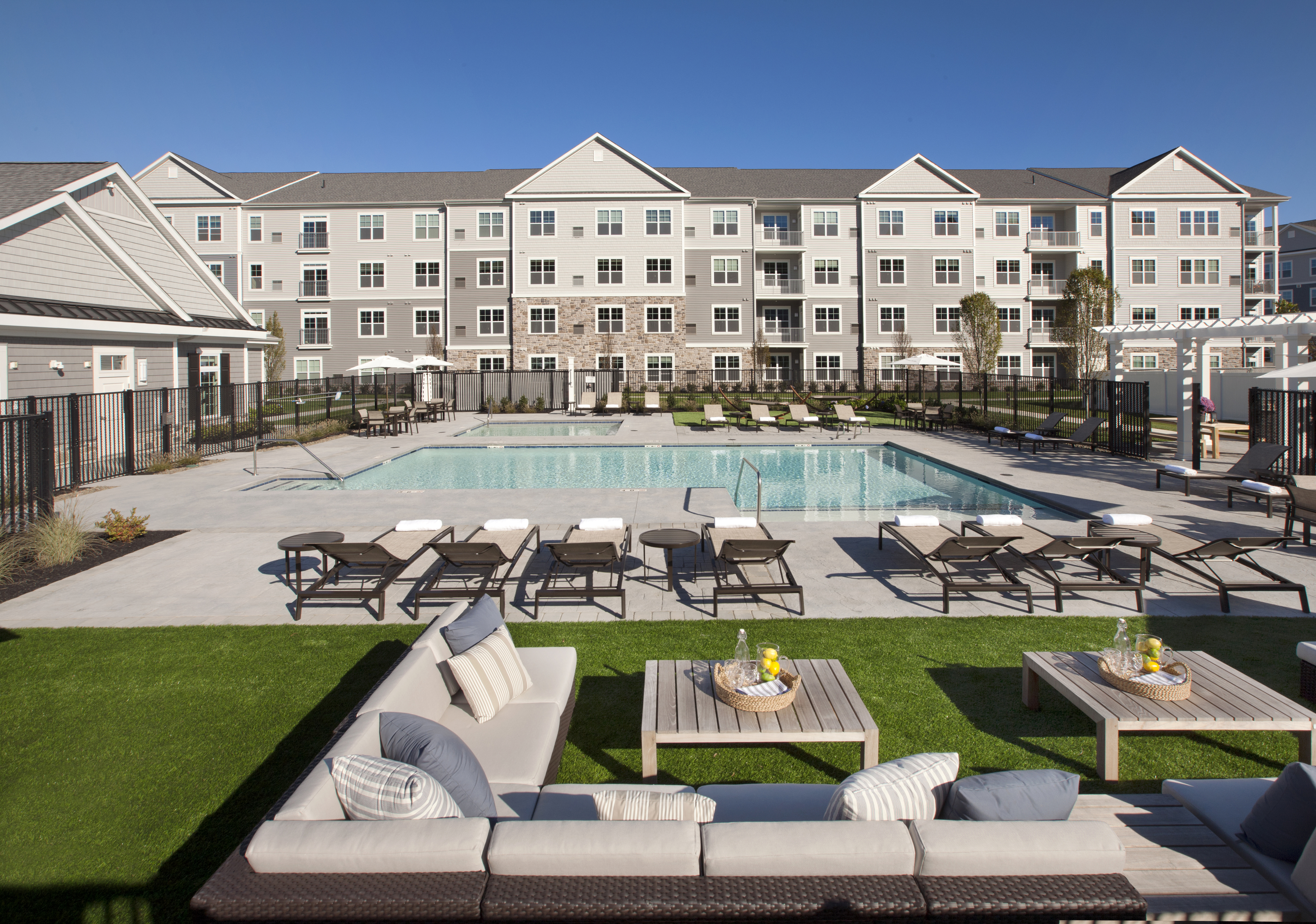 View of Pool Area, Showing Loungers, Outdoor Couches, and Apartment Building in the Background at Parc Westborough Apartments