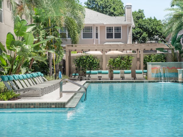 View of Pool, Showing Loungers, Pergola, and Apartment Building in Background at Cottonwood Bayview Apartments