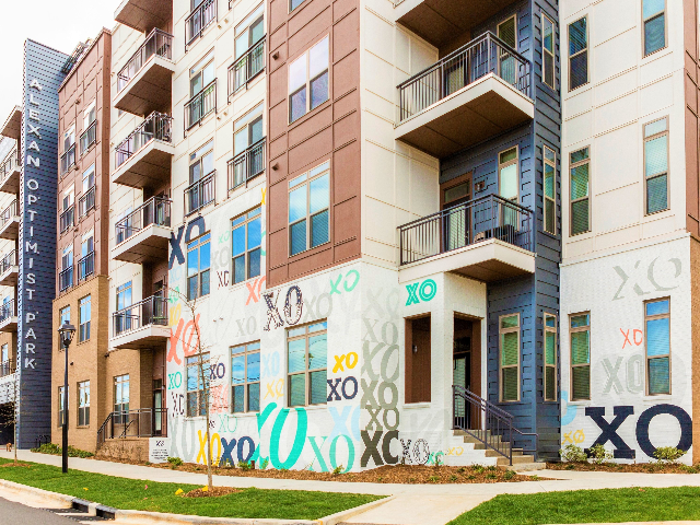 Enjoy Our Community Exterior, With View of XO Mural, Walk-Out Patios, and Balconies at Alton Optimist Park Apartments