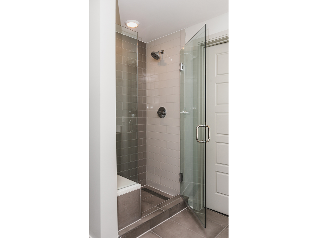 Walk-in glass showers with tile and bench seating