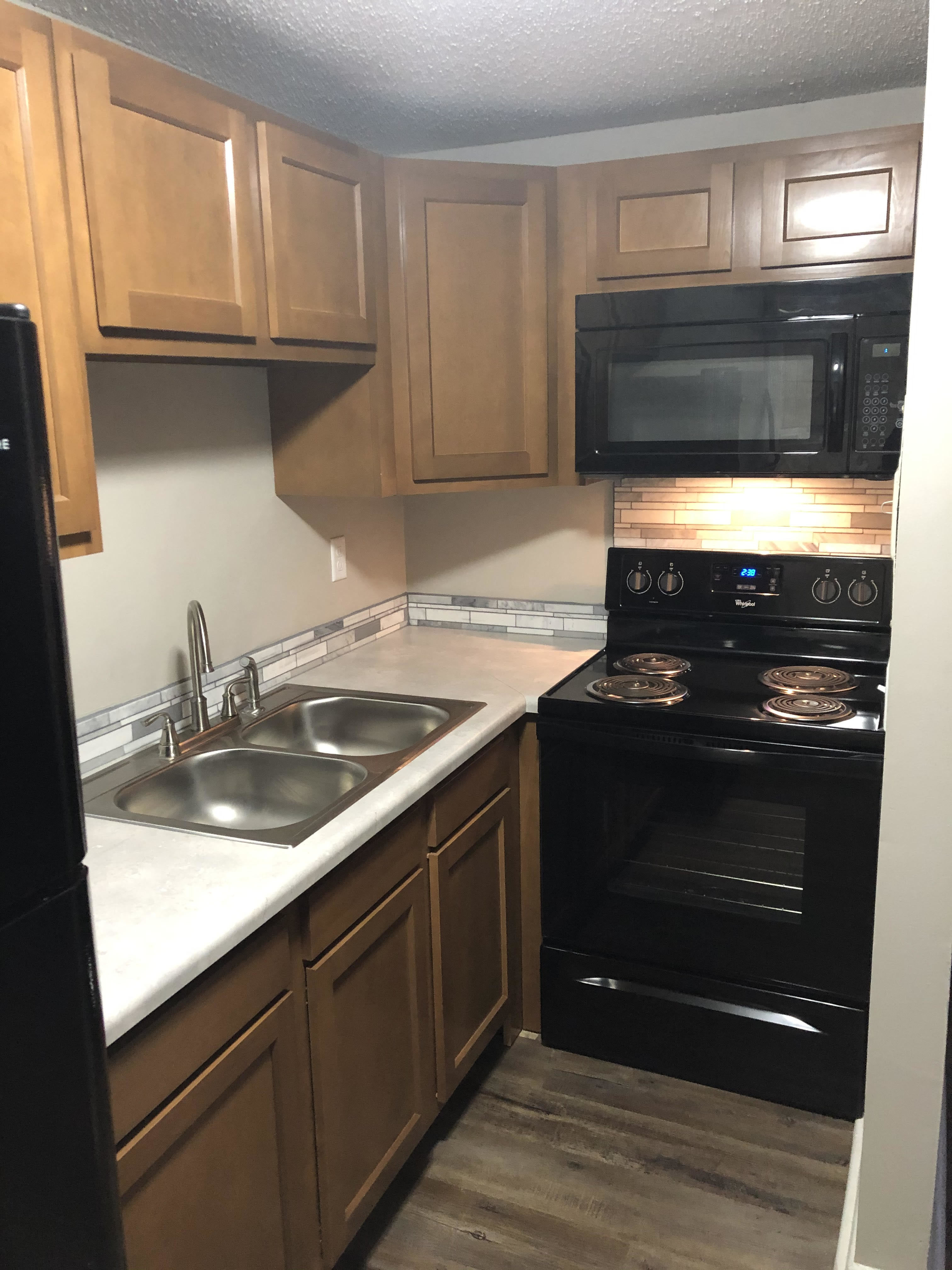 Newly renovated kitchen with black appliances and light brown cabinets