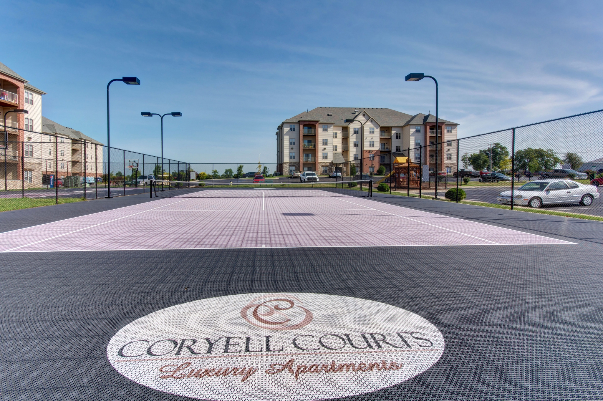 Coryell Courts Apartments amenity tennis court overlooking the exterior apartment building